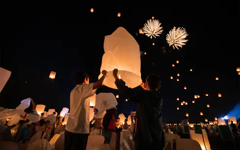 Participants release lanterns at Yeepeng Lanna Festival 2023 with fireworks in the night sky.