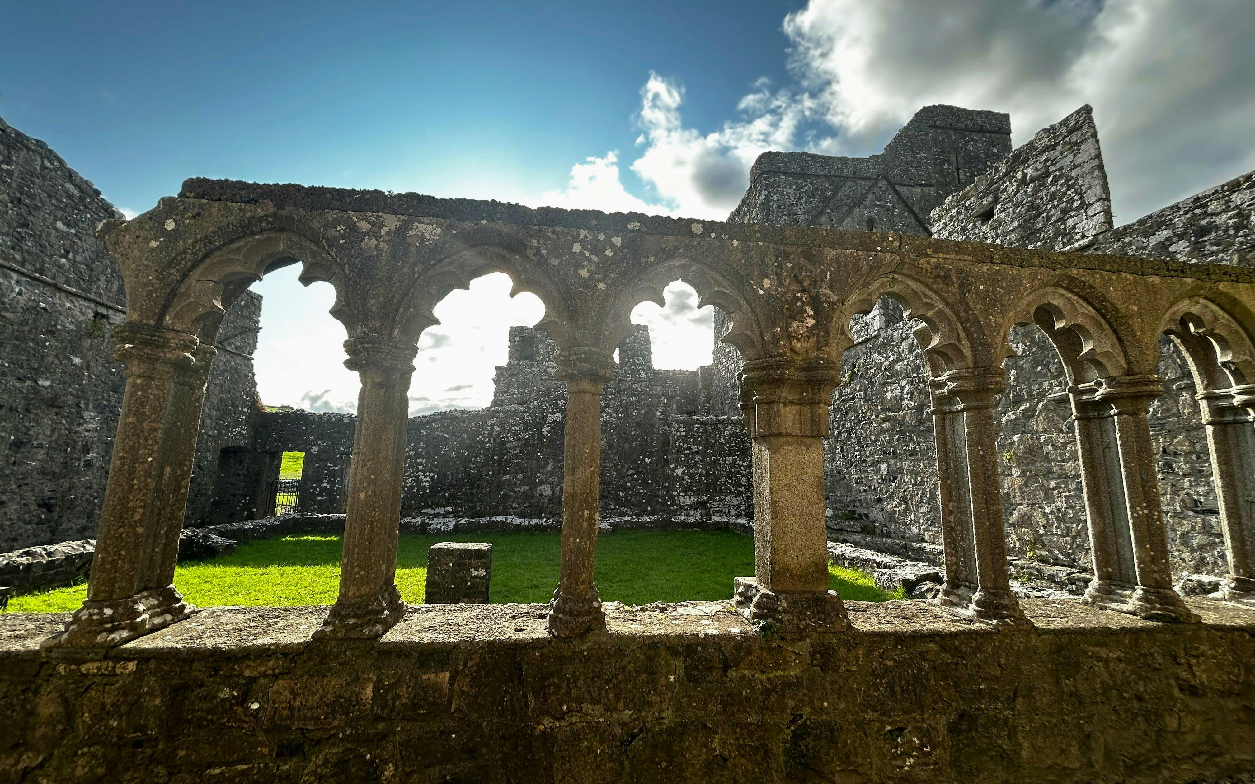 Stone arches and ruins at Trim Castle, Ireland, with sunlight filtering through.