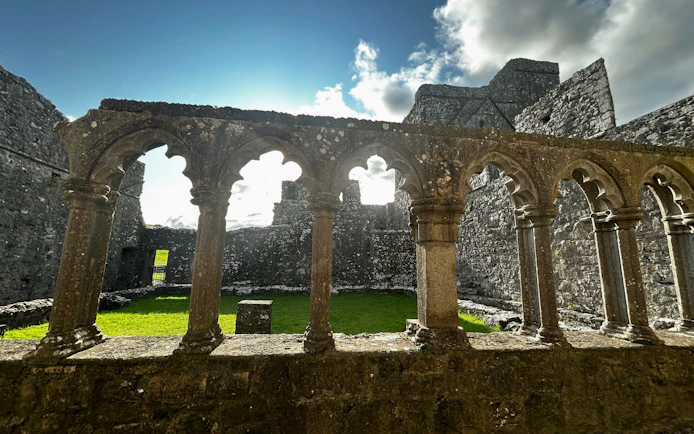 Stone arches and ruins at Trim Castle, Ireland, with sunlight filtering through.