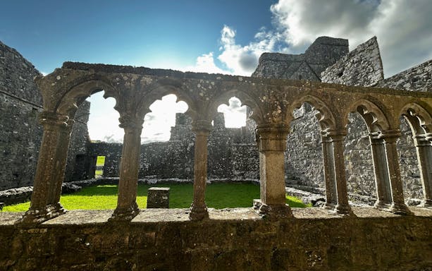 Stone arches and ruins at Trim Castle, Ireland, with sunlight filtering through.