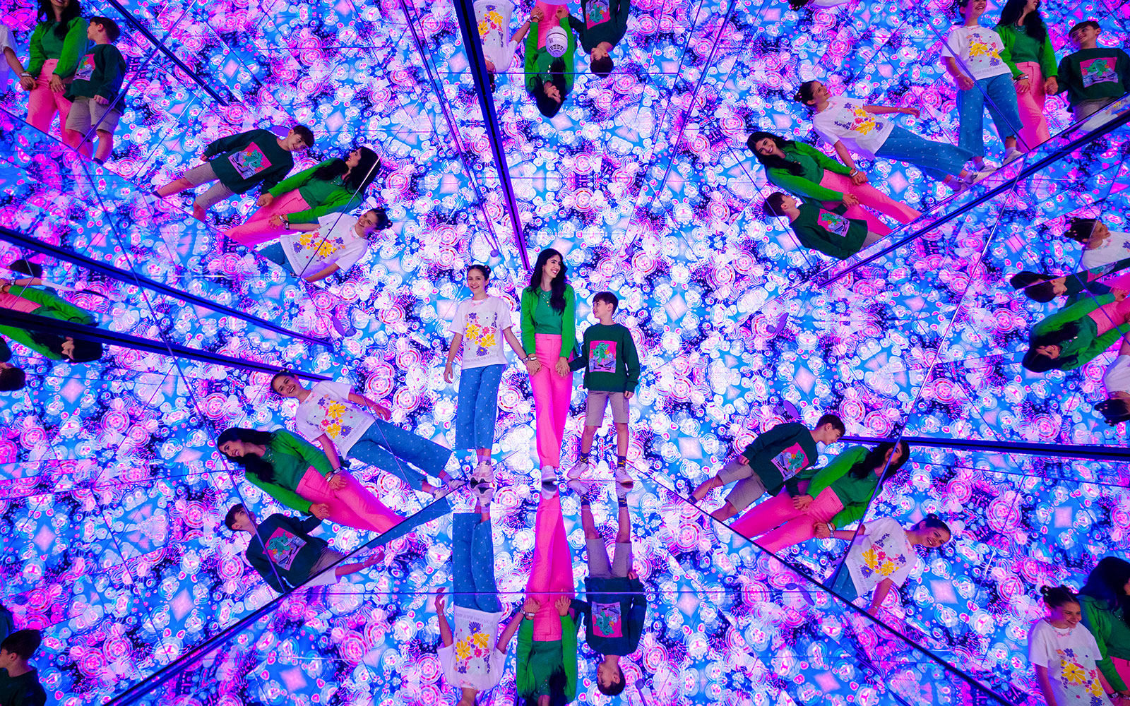 Tourists exploring mirrored room with vibrant lights at House of Hype, Dubai.