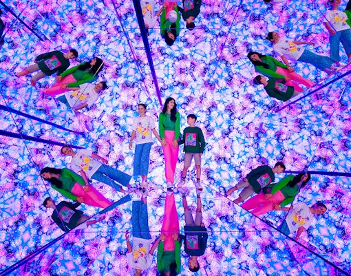 Tourists exploring mirrored room with vibrant lights at House of Hype, Dubai.