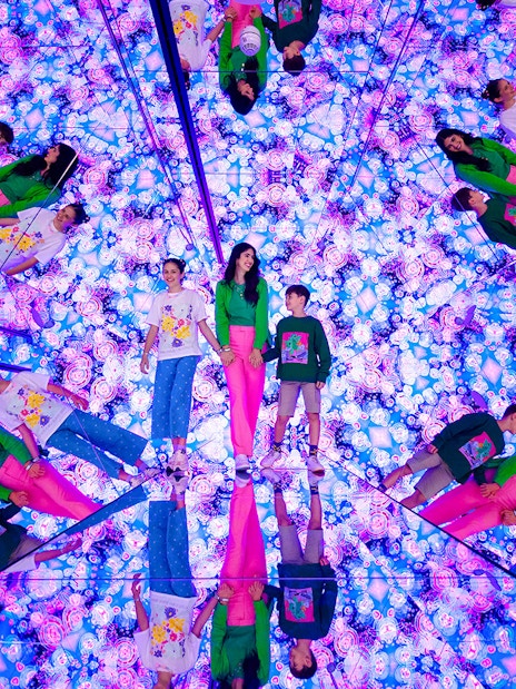 Tourists exploring mirrored room with vibrant lights at House of Hype, Dubai.
