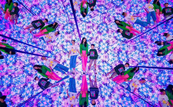 Tourists exploring mirrored room with vibrant lights at House of Hype, Dubai.