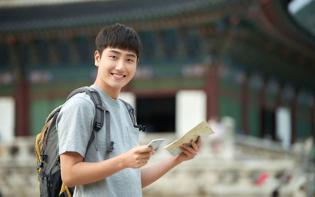 Traveler with map and phone at Gyeongbokgung Palace, Seoul, South Korea.