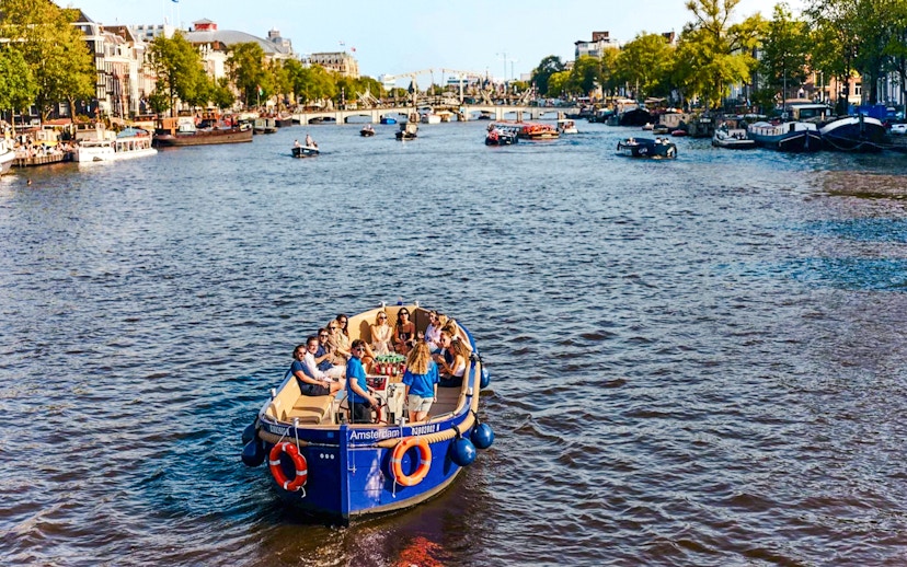 Canal cruise boat with passengers on Amsterdam's Red Light District waterway.