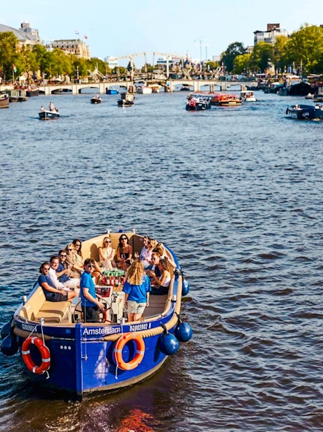 Canal cruise boat with passengers on Amsterdam's Red Light District waterway.