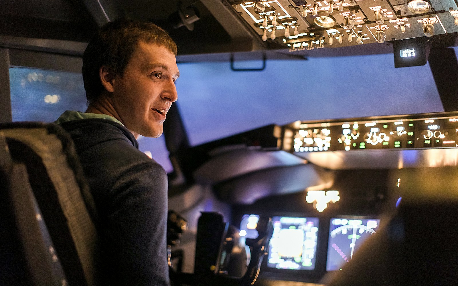 Young man piloting a plane in a flight simulator cockpit.