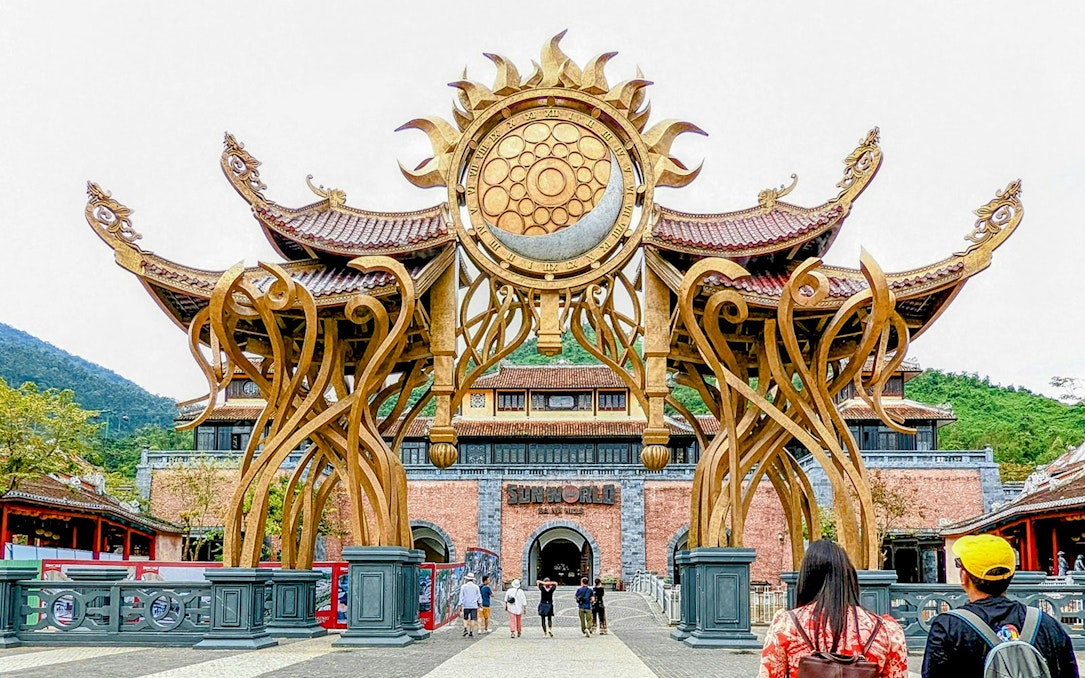 Entrance of Sun World Ba Na Hill with ornate golden arch and visitors walking through.