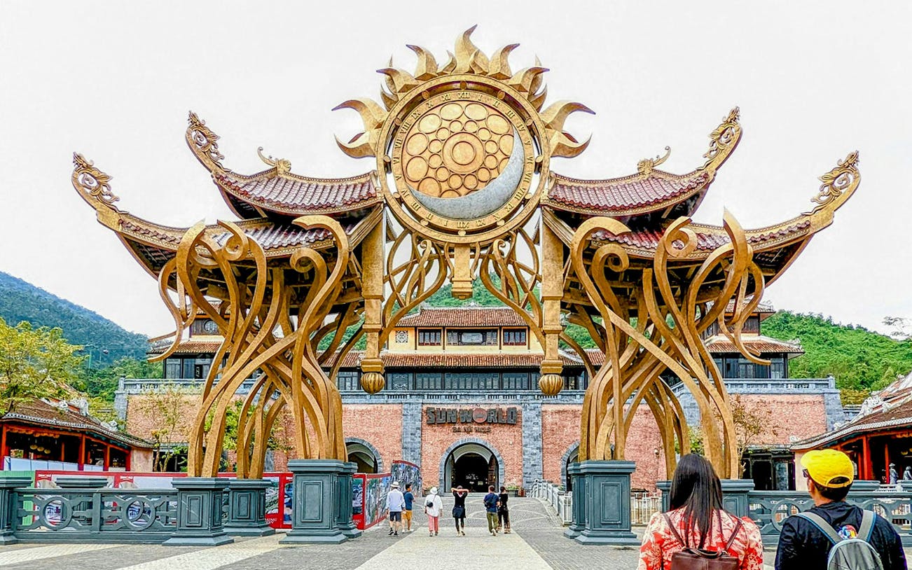 Entrance of Sun World Ba Na Hill with ornate golden arch and visitors walking through.
