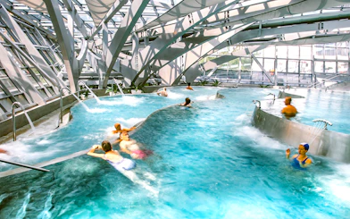 Visitors enjoying thermal pools at Caldea spa in Andorra with modern architecture.