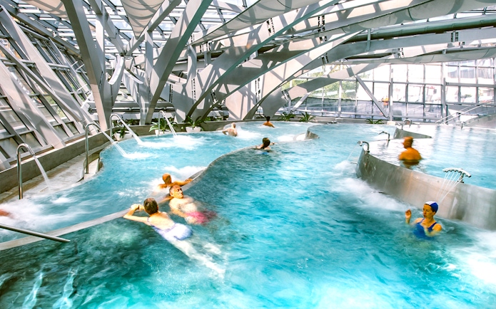 Visitors enjoying thermal pools at Caldea spa in Andorra with modern architecture.