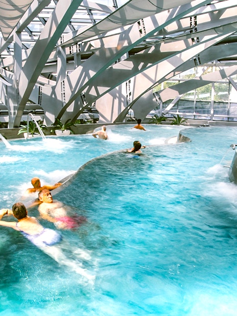 Visitors enjoying thermal pools at Caldea spa in Andorra with modern architecture.