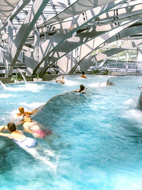 Visitors enjoying thermal pools at Caldea spa in Andorra with modern architecture.