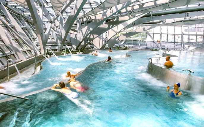 Visitors enjoying thermal pools at Caldea spa in Andorra with modern architecture.