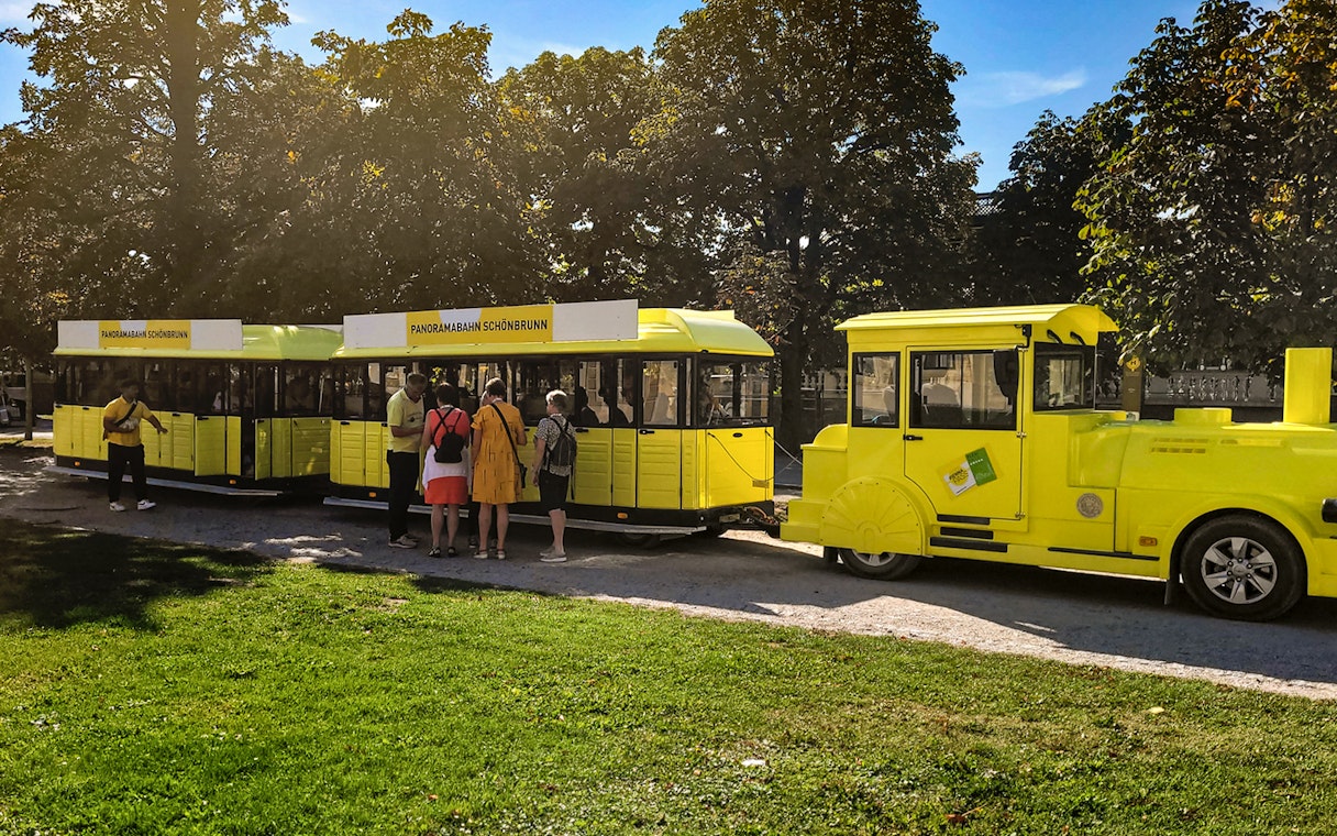 Panorama train at Schönbrunn Palace with visitors boarding.