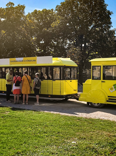 Panorama train at Schönbrunn Palace with visitors boarding.