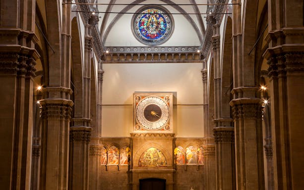 Interior of Florence Cathedral featuring ornate clock and stained glass window.