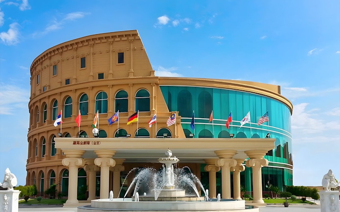 Colosseum Show Pattaya building with international flags and fountain.