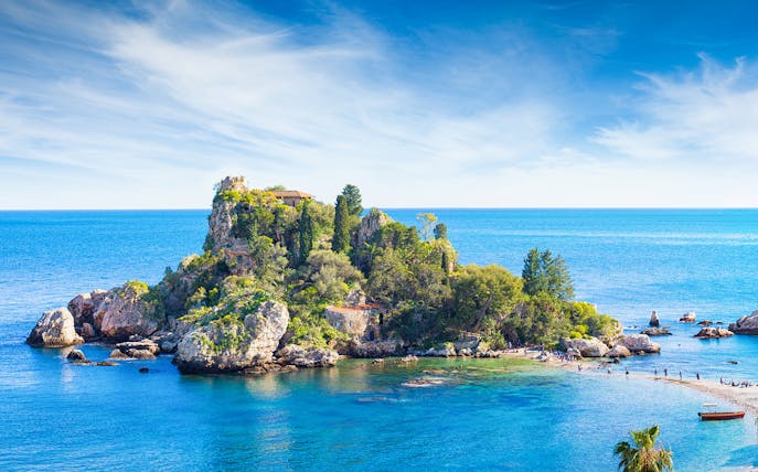Taormina Island with lush greenery surrounded by blue sea and rocky coastline.