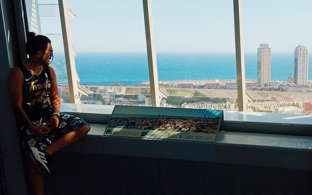Tourist enjoying city and sea view from inside Glories Skyline Tower, Barcelona.