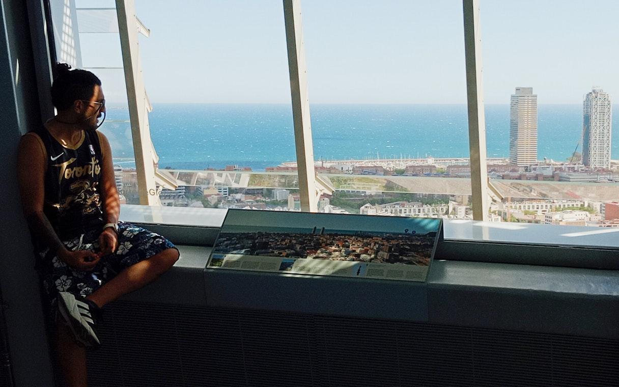 Tourist enjoying city and sea view from inside Glories Skyline Tower, Barcelona.