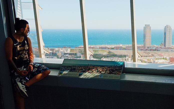Tourist enjoying city and sea view from inside Glories Skyline Tower, Barcelona.