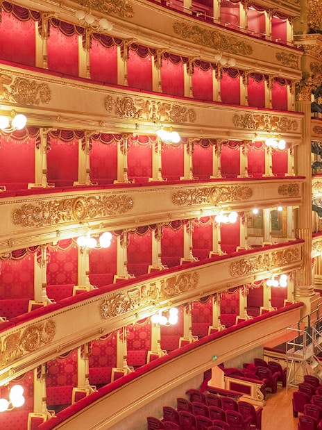 Balconies and stage of La Scala Theatre, Milan, with ornate gold detailing and red velvet seating.