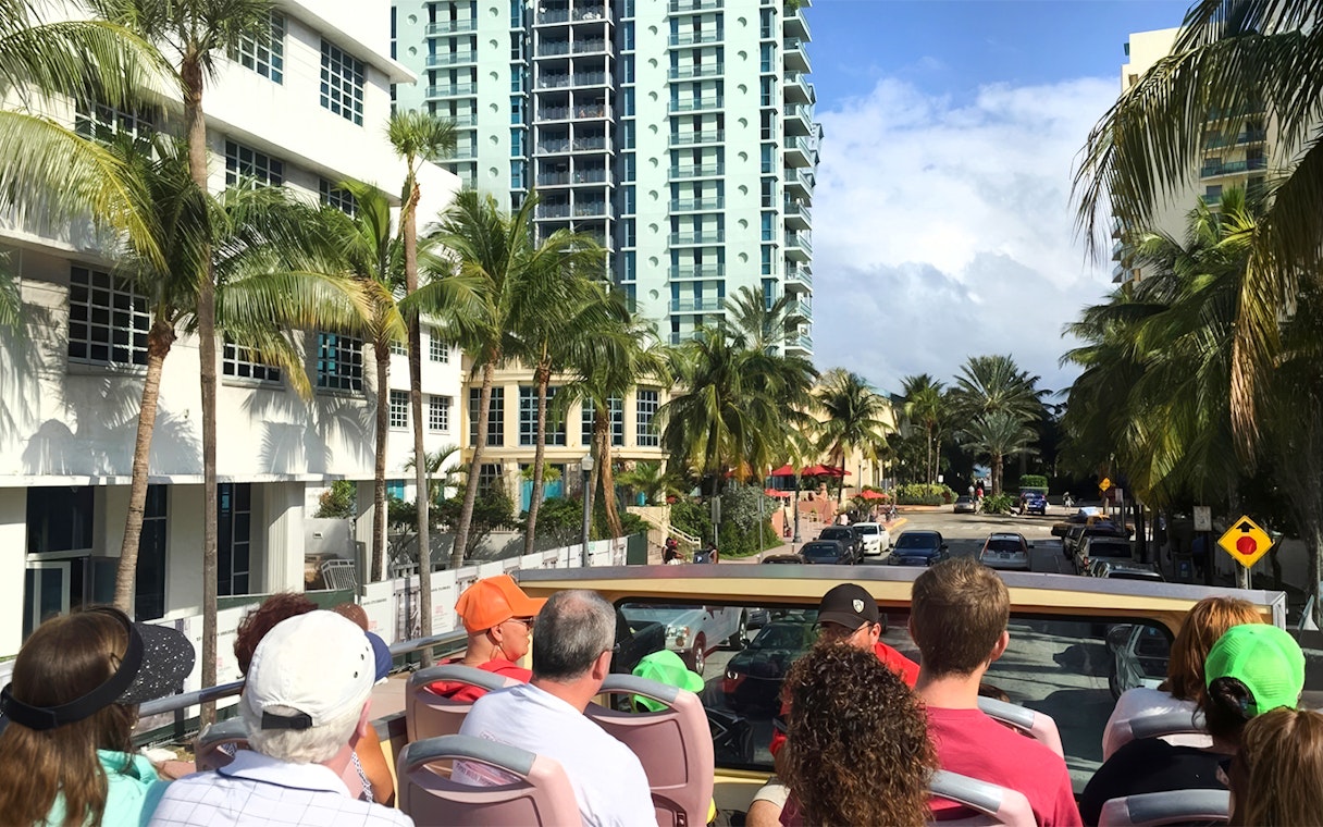 Open-top bus tour through Miami with palm trees and high-rise buildings.
