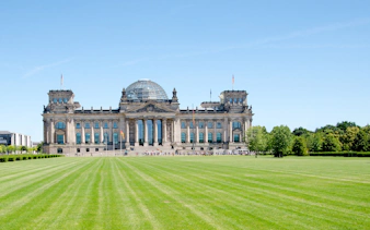 Reichstag building in Berlin, Germany, with a glass dome and expansive lawn.