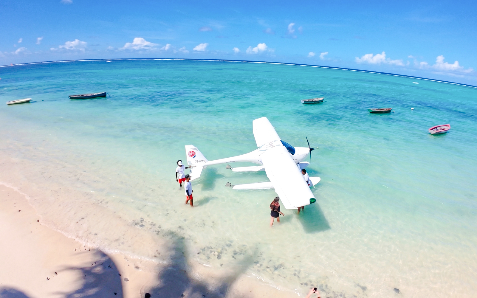 Seaplane on turquoise waters with people on a beach in Mauritius.