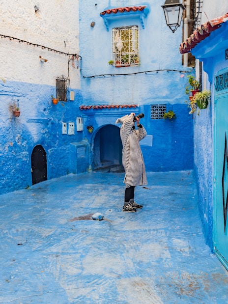 Photographer capturing blue alley in Chefchaouen, Morocco.