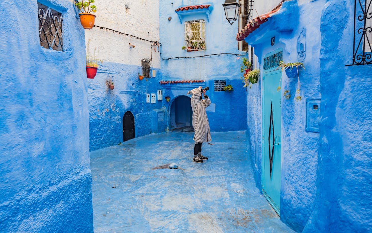 Photographer capturing blue alley in Chefchaouen, Morocco.