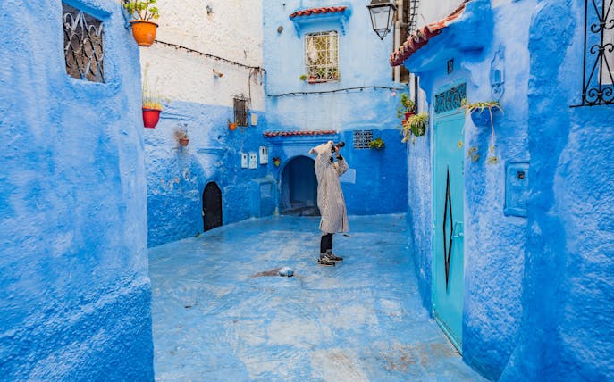 Photographer capturing blue alley in Chefchaouen, Morocco.