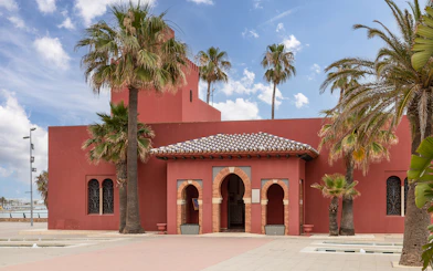 Red Arab-style Bill Bil Castle with palm trees along Benalmadena coast.