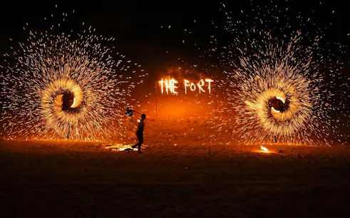 Fire performer during Dubai desert safari with "The Fort" in flames.