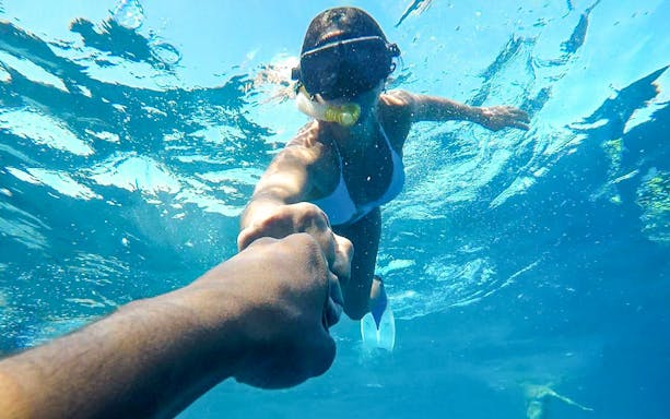 Snorkeler holding hand underwater during Hurghada boat tour.