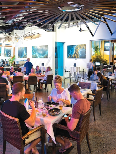Dining area at Cairns Aquarium by Twilight with guests enjoying meals near large aquarium display.