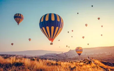 Hot air balloons over Cappadocia landscape at sunrise.