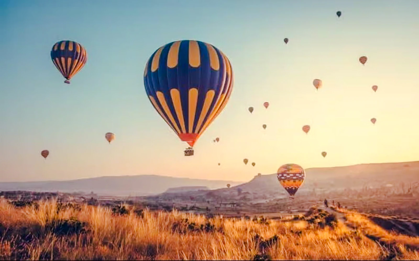 Hot air balloons over Cappadocia landscape at sunrise.