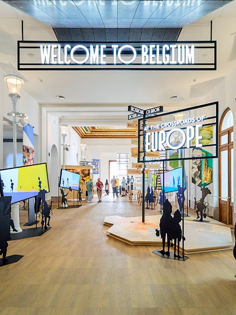 Brussels museum exhibit with "Welcome to Belgium" sign, part of hop-on hop-off bus tour.