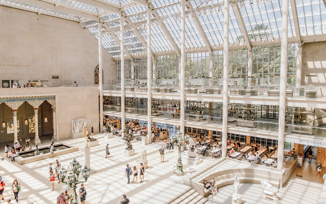 Visitors exploring the sunlit atrium of the Metropolitan Museum of Art, New York.