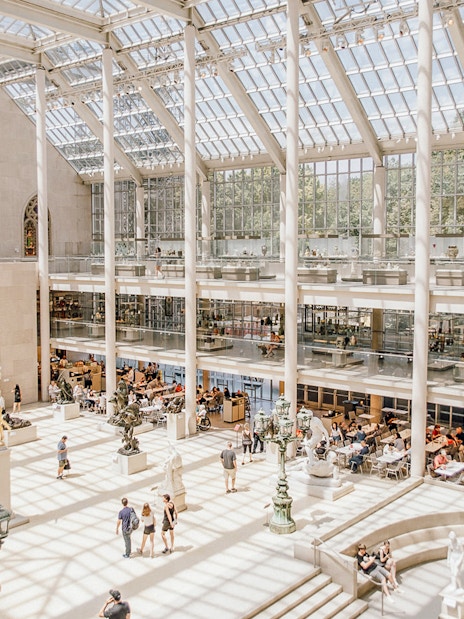 Visitors exploring the sunlit atrium of the Metropolitan Museum of Art, New York.