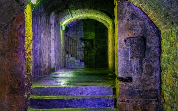 Dimly lit stone corridor in Edinburgh's Terror Tour with arched ceiling and stairs.