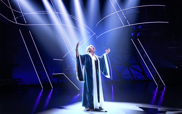 Performer on stage under dramatic lighting in a scene from the Lempicka show.
