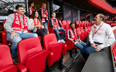 Visitors on a VIP tour at Johan Cruijff ArenA, Amsterdam, enjoying drinks and wearing scarves.