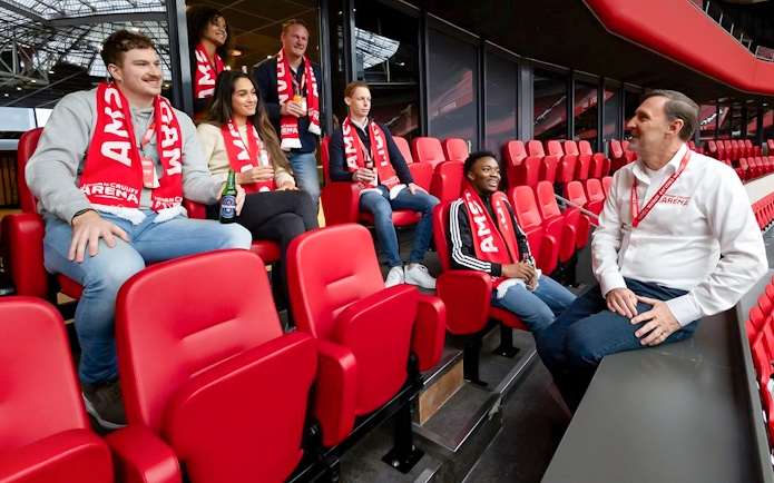 Visitors on a VIP tour at Johan Cruijff ArenA, Amsterdam, enjoying drinks and wearing scarves.