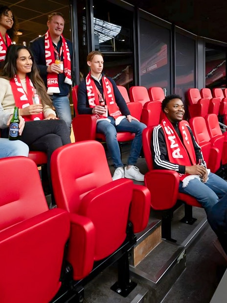 Visitors on a VIP tour at Johan Cruijff ArenA, Amsterdam, enjoying drinks and wearing scarves.