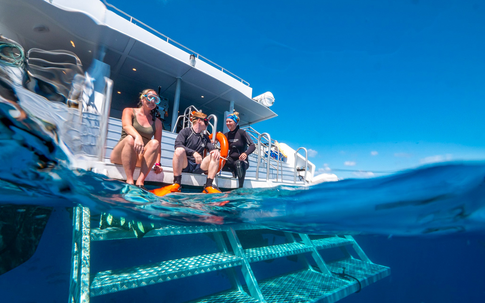 Tourists snorkelling in clear blue waters of Great Barrier Reef during full day cruise from Cairns.