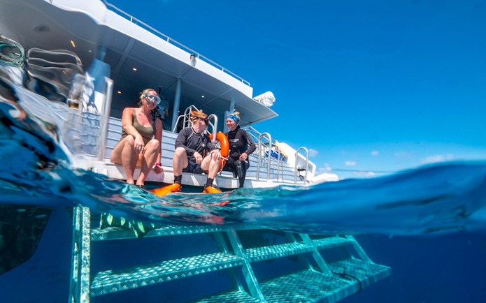 Tourists preparing to snorkel from a boat in the Great Barrier Reef's clear waters.